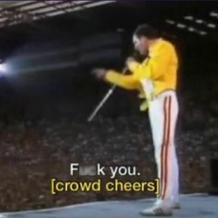 '90s musician in yellow jacket on stage, performing energetically to a cheering crowd.
