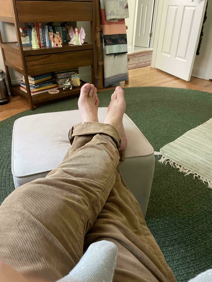Confusing perspective with feet and pant legs, giving the illusion of reversed legs on an ottoman.