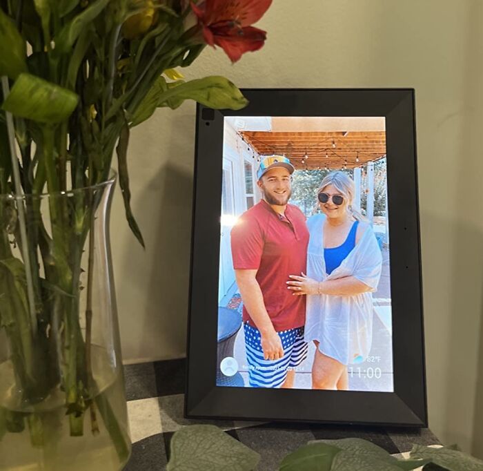 Smart home display showing a couple's photo, next to a vase of flowers on a table.