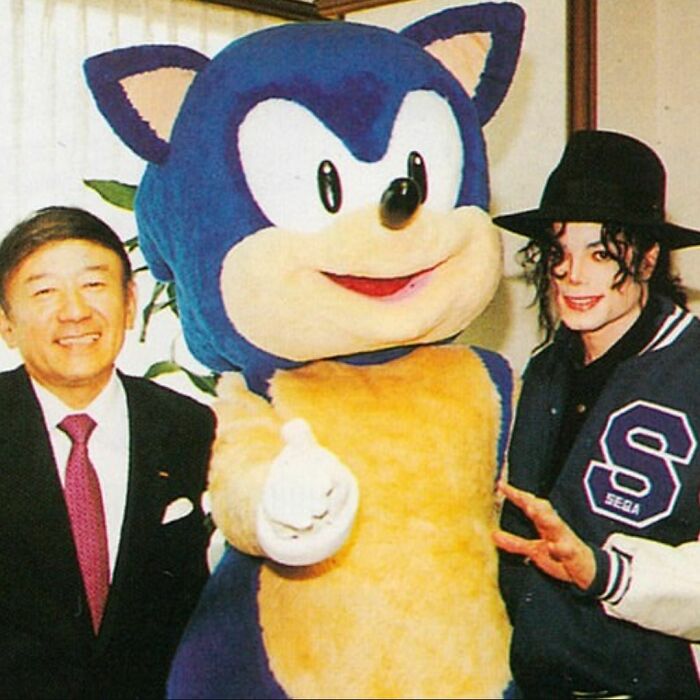 Man with Sonic the Hedgehog mascot and person in Sega jacket, capturing a moment from the ‘90s.