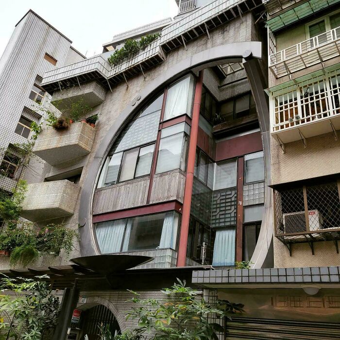 Unique bizarre building with a large circular frame and modern glass windows in an urban residential area.