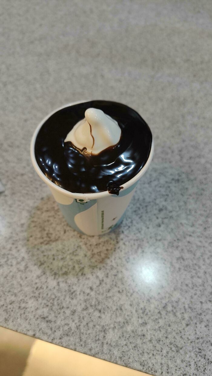 Soft serve ice cream with extra chocolate sauce on a countertop.
