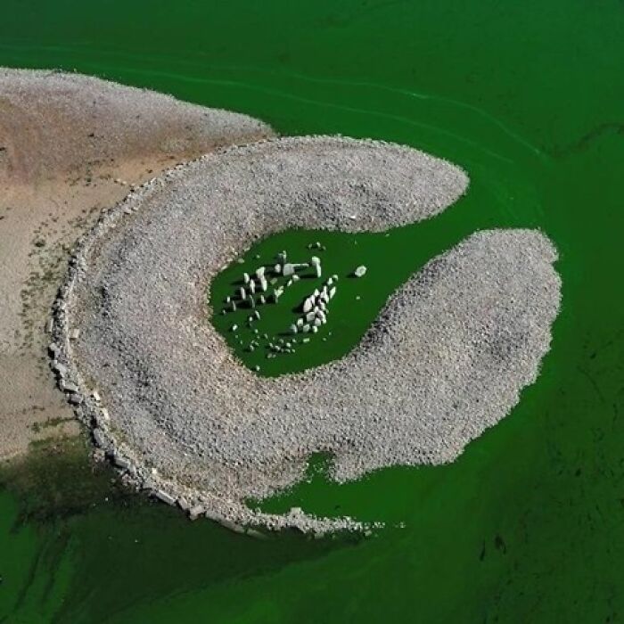 Ancient stone circle partially submerged in a green lake showing curious history.