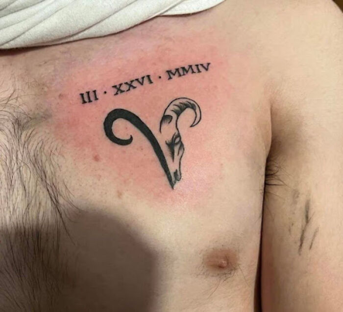 Aries tattoo on chest with Roman numerals, featuring a ram's head design.
