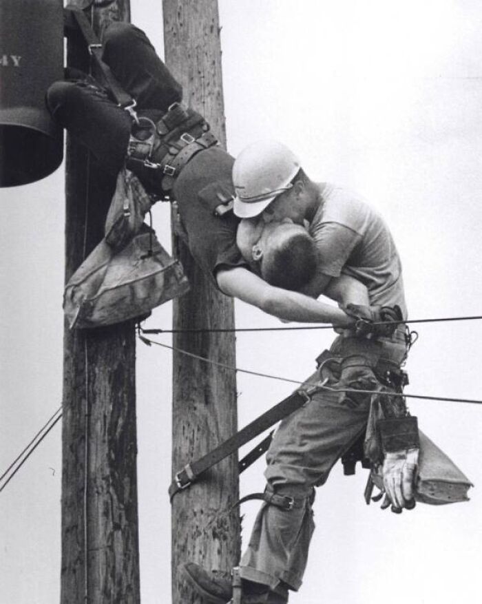 Utility worker performs mouth-to-mouth resuscitation on a suspended colleague, showcasing a surprising history moment.