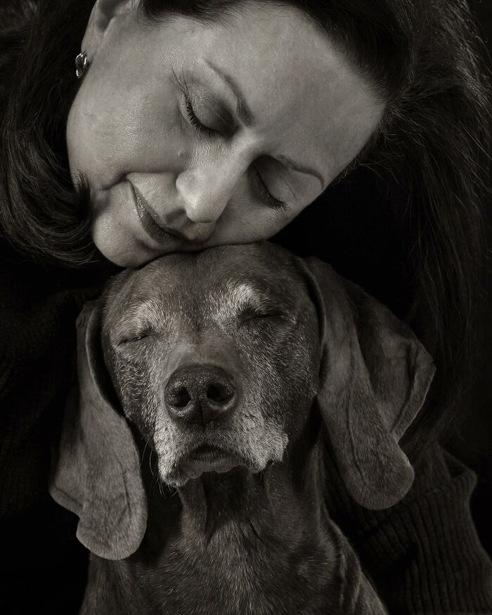Close-up black and white portrait of a woman and her dog sharing a peaceful moment, featured in dog photography awards.