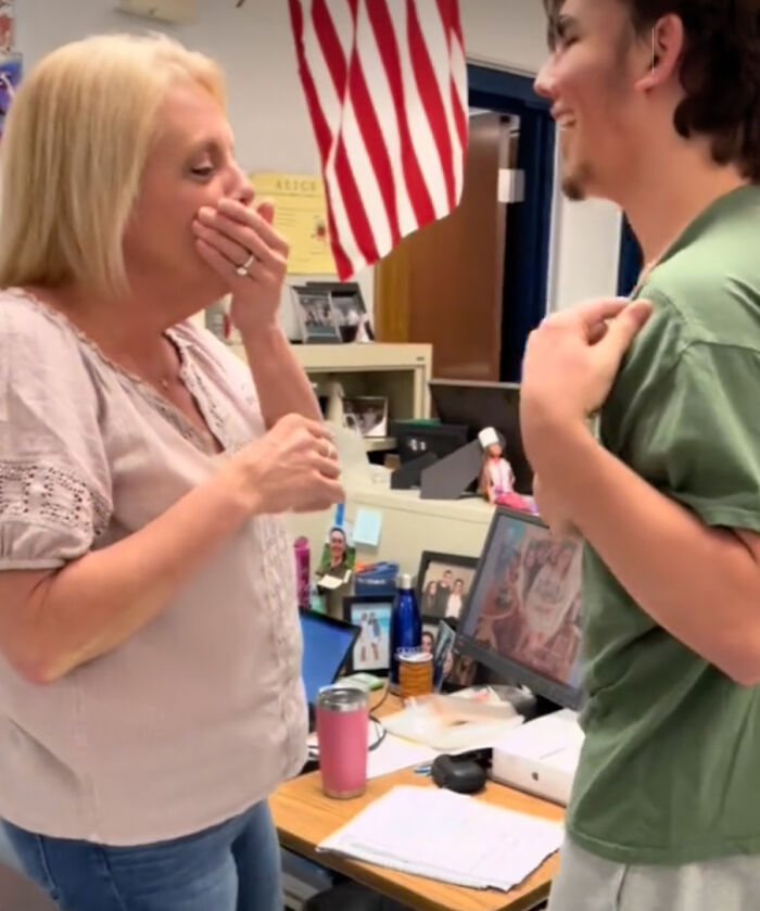 Teacher emotional as student reveals tattoo of her note on his chest, standing in a classroom setting.