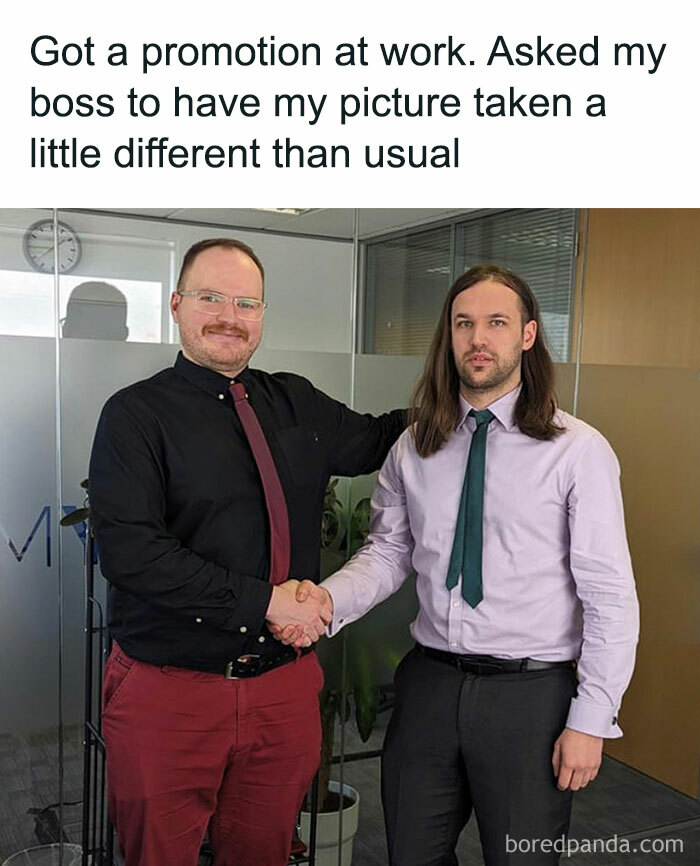 A "The Office" meme featuring two men in an office setting shaking hands. The man on the left is dressed in a black shirt with a red tie and red pants, while the man on the right is dressed in a lavender shirt with a green tie and gray pants. The text above the image reads, "Got a promotion at work. Asked my boss to have my picture taken a little different than usual." The scene humorously resembles the style of a formal photo but with a quirky twist, reminiscent of the show's humor.