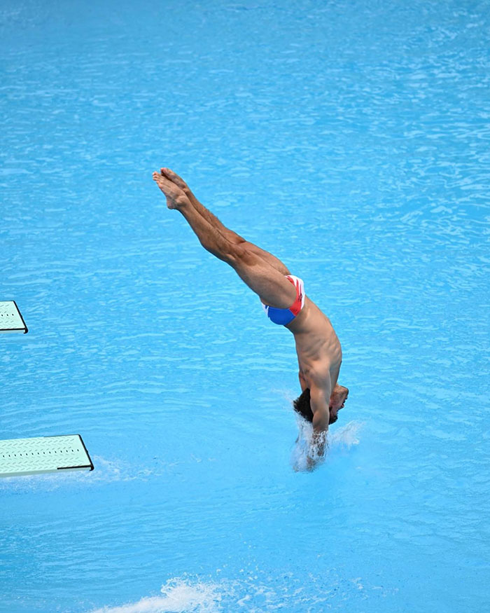 Olympic diver performing a dive in a colorful swimsuit, underwater entry, showcasing athletic skill. Olympic diver performing a dive in a colorful swimsuit, underwater entry, showcasing athletic skill.