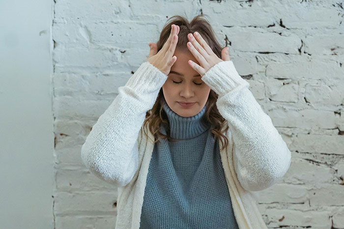 Woman in a white sweater and blue turtleneck showing stress, illustrating the impact of terrifying helicopter parenting examples shared online