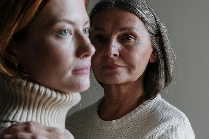 Close-up of two women with serious expressions, illustrating the emotional impact of helicopter parenting behavior.