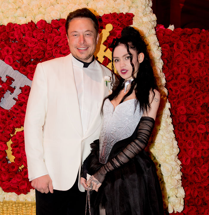 Elon Musk and Grimes standing together at a formal event.
