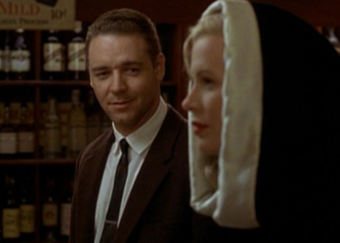 Man in suit looking at woman in hooded coat inside a dimly lit bar, illustrating film adaptations that outdid books.