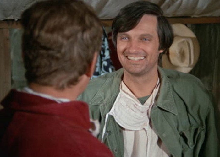 Man smiling in an indoor setting while wearing a green jacket, illustrating surprising film adaptations that outdid their books.