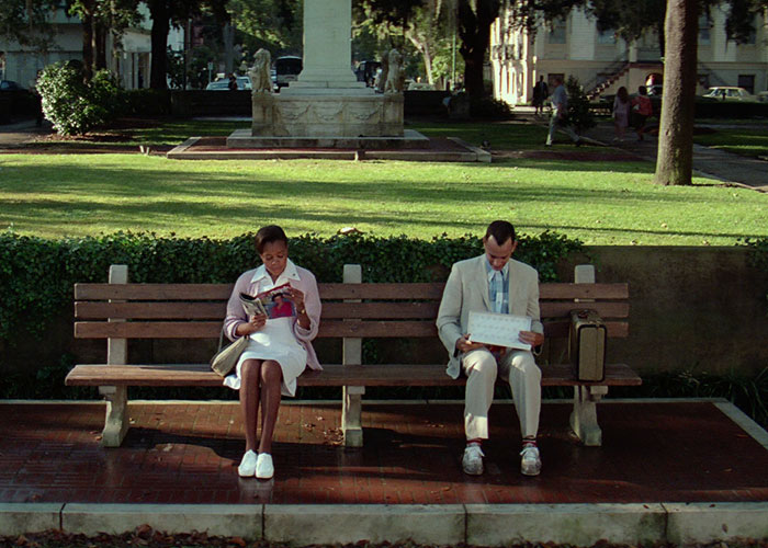 Two people sitting on a bench in a park, representing surprising film adaptations that outdid their books.