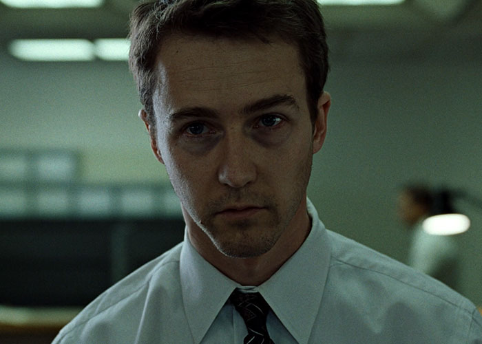 Man with bruised eye in office setting, representing surprising film adaptations that outdid their books.