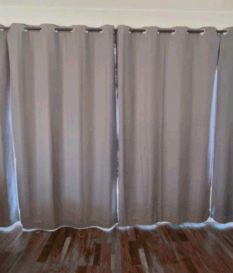 Smart home curtains opening automatically in a cozy living space with wooden floors.