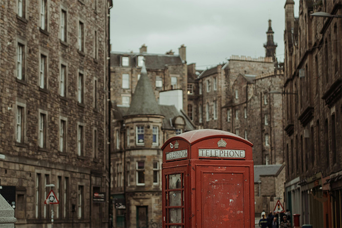 Red British telephone booth on a historic cobblestone street in a city tourists rave about, place visited