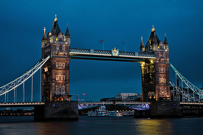 Illuminated Tower Bridge at dusk, iconic place visited by tourists along the Thames in London.