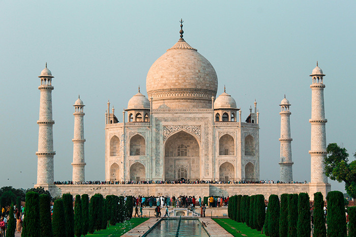 Taj Mahal as a place visited, white marble mausoleum with reflecting pool, gardens and crowds at sunrise