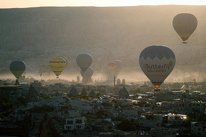 Hot air balloons over Cappadocia at sunrise, ancient rock formations and village roofs—an unforgettable place visited