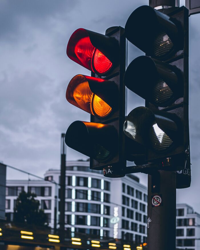 Traffic light showing red and amber signals at an urban intersection under cloudy sky, representing trivial moments making pregnant women emotional.