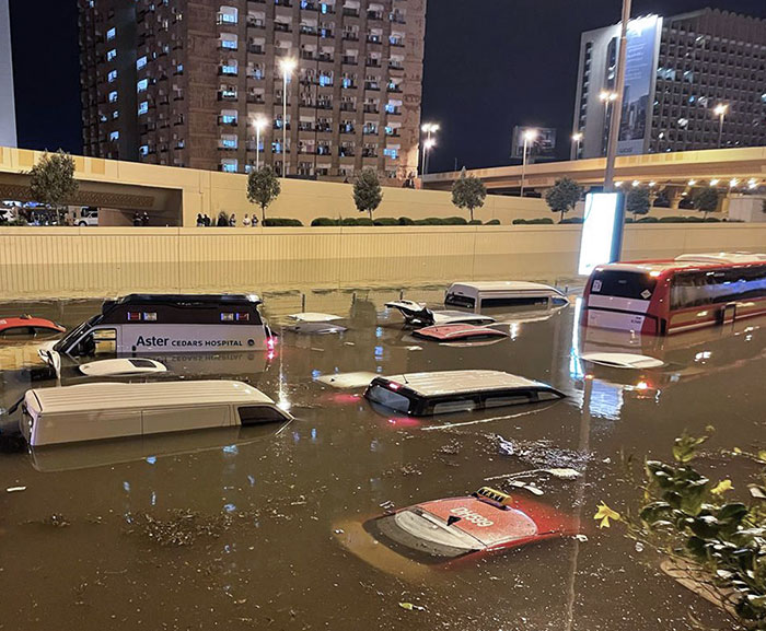 Flooded street with multiple submerged vehicles at night, showcasing nature's power on its own terms.
