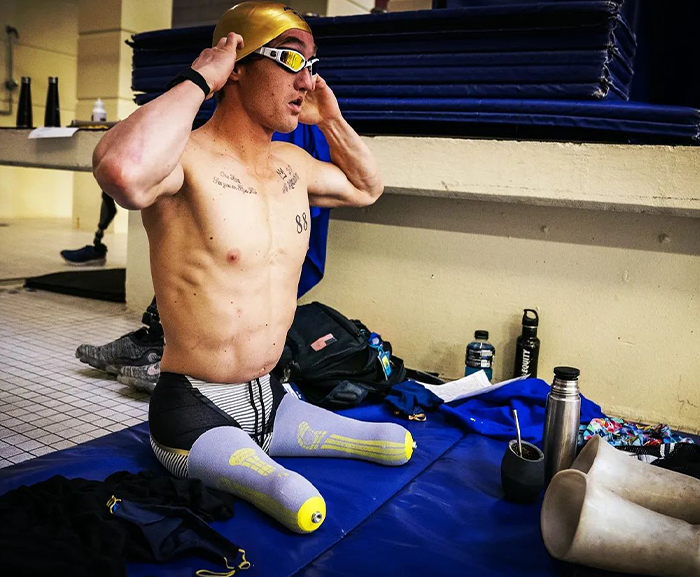 Athlete preparing for swimming, showcasing tattoos, highlighting division between Paris Paralympics and Olympics rulings.