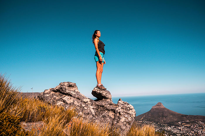 A woman standing on a rock overlooking a coastal landscape, symbolizing world travelers ranking friendliest nations.