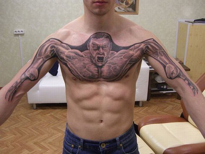 "Tattoo of a muscular figure stretches across a man's chest and arms in a unique design."
