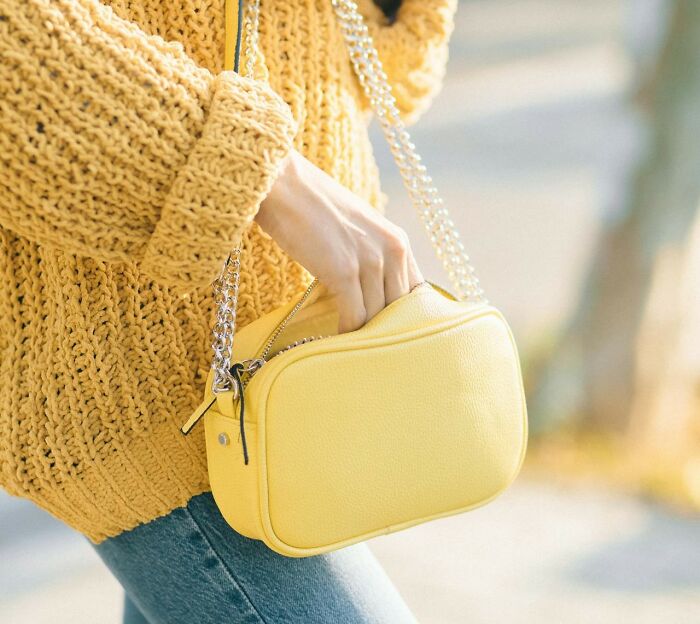 Woman wearing a textured yellow sweater and carrying a small yellow purse, illustrating things women want men to understand.