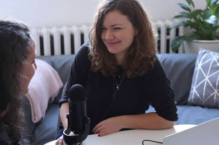 Two women recording a podcast, discussing jobs once respected but associated with awful people in modern times.