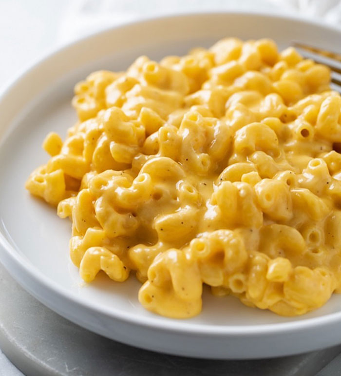 A lunch idea featuring creamy macaroni and cheese served on a white plate, with perfectly coated macaroni in a rich cheese sauce. A lunch idea featuring creamy macaroni and cheese served on a white plate, with perfectly coated macaroni in a rich cheese sauce.