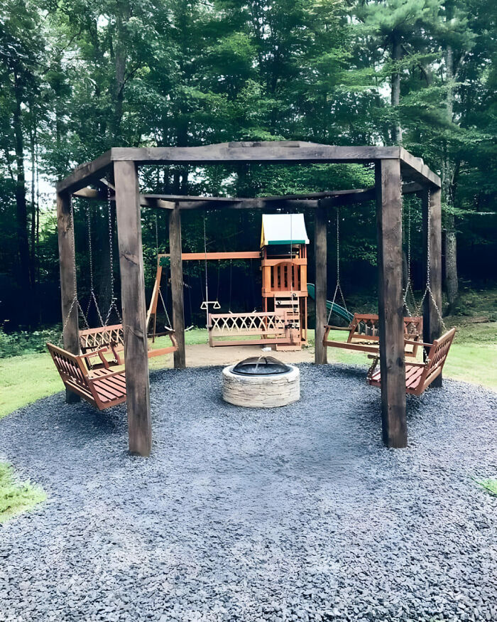 Woodworkers outdoor project featuring a wooden swing set with four benches around a stone fire pit in a backyard.