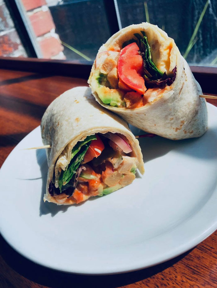 A lunch idea featuring two Indian-spiced chickpea wraps, filled with vegetables and served on a white plate by a window, with natural light. A lunch idea featuring two Indian-spiced chickpea wraps, filled with vegetables and served on a white plate by a window, with natural light.