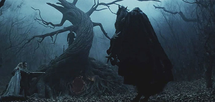 A dark, eerie scene from the movie Sleepy Hollow featuring a cloaked figure on horseback, presumably the Headless Horseman, standing before a twisted, gnarled tree in a fog-filled, leafless forest. A large, ominous opening is visible at the base of the tree, and in the background, two figures can be seen cautiously approaching, adding to the suspenseful atmosphere. The scene is shrouded in deep shadows, enhancing its supernatural and foreboding tone. A dark, eerie scene from the movie Sleepy Hollow featuring a cloaked figure on horseback, presumably the Headless Horseman, standing before a twisted, gnarled tree in a fog-filled, leafless forest. A large, ominous opening is visible at the base of the tree, and in the background, two figures can be seen cautiously approaching, adding to the suspenseful atmosphere. The scene is shrouded in deep shadows, enhancing its supernatural and foreboding tone.