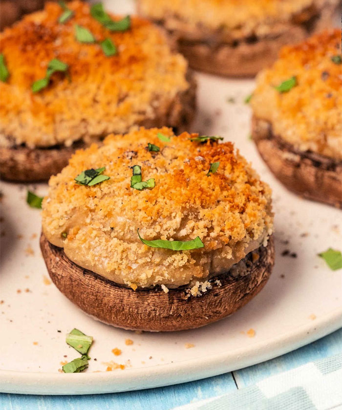 A lunch idea featuring creamy vegetarian stuffed mushrooms topped with golden breadcrumbs and garnished with fresh herbs on a white plate. A lunch idea featuring creamy vegetarian stuffed mushrooms topped with golden breadcrumbs and garnished with fresh herbs on a white plate.