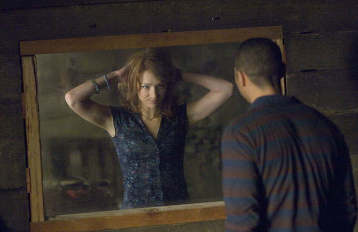 A scene from the movie The Cabin in the Woods featuring a young woman adjusting her hair in front of a mirror, while a man stands on the other side, watching her through what appears to be a one-way window. The setting is inside a rustic, wooden cabin, creating a tense and mysterious atmosphere. The woman seems unaware of being observed, while the man looks intently, heightening the feeling of secrecy and unease. A scene from the movie The Cabin in the Woods featuring a young woman adjusting her hair in front of a mirror, while a man stands on the other side, watching her through what appears to be a one-way window. The setting is inside a rustic, wooden cabin, creating a tense and mysterious atmosphere. The woman seems unaware of being observed, while the man looks intently, heightening the feeling of secrecy and unease.