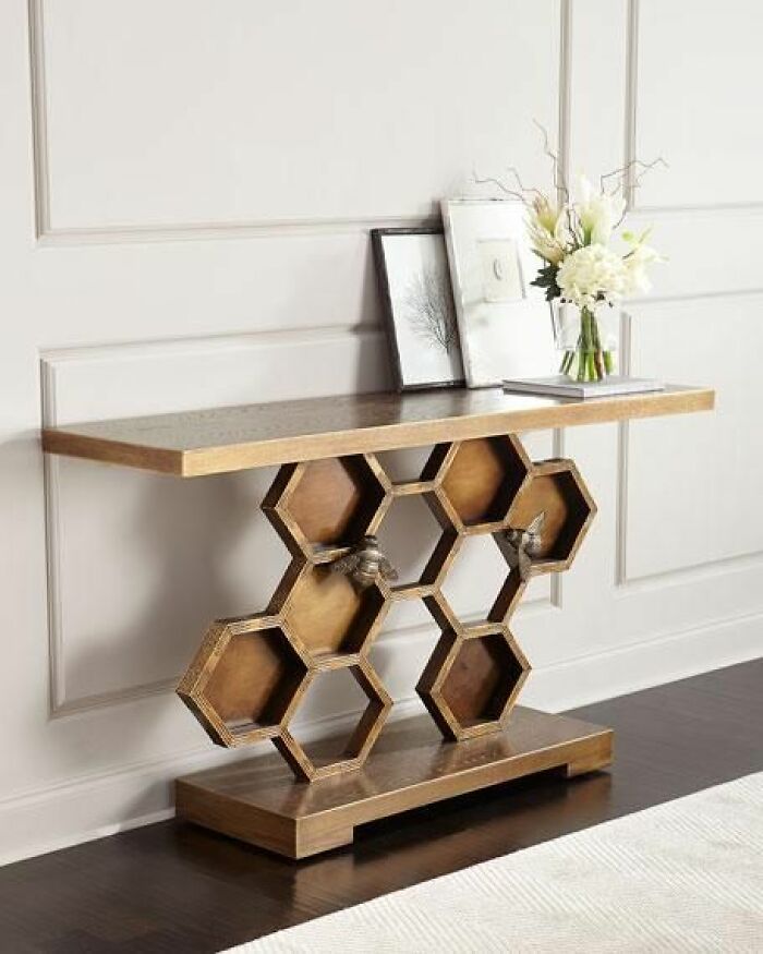 Woodworker's honeycomb-style wooden console table with decorative bee figurines and floral arrangement on top in a modern room.