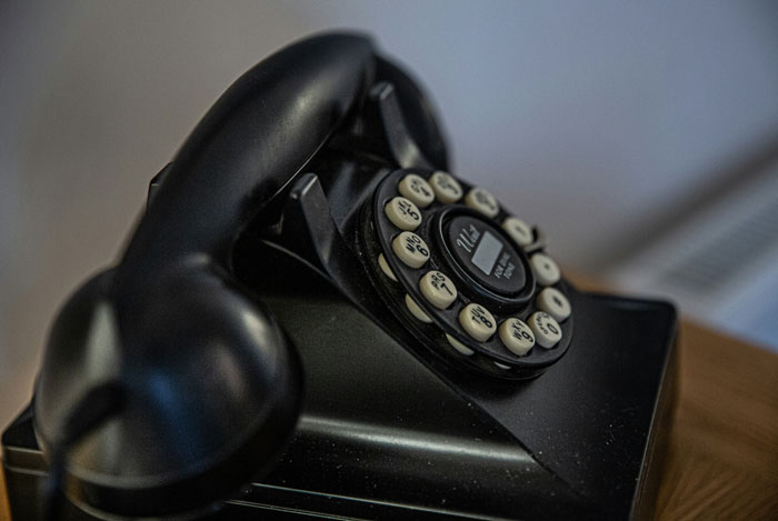 Black vintage rotary phone with handset resting on the base, representing unhinged and disturbing voicemails concept.