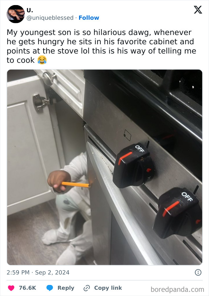 Child sitting inside kitchen cabinet pointing at stove knobs, a funny parenting tweet about kids' quirky behavior.