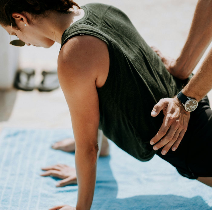 A personal trainer assisting a client during a workout, illustrating one of the jobs once respected but done by awful people.