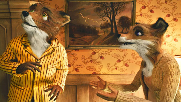 A scene from the movie Fantastic Mr. Fox featuring two anthropomorphic foxes in a cozy room with patterned wallpaper and a painting of a stormy landscape in the background. The fox on the left is wearing yellow-striped pajamas, while the one on the right wears a beige sweater, both with expressive facial features and engaged in conversation, with concerned body language. A scene from the movie Fantastic Mr. Fox featuring two anthropomorphic foxes in a cozy room with patterned wallpaper and a painting of a stormy landscape in the background. The fox on the left is wearing yellow-striped pajamas, while the one on the right wears a beige sweater, both with expressive facial features and engaged in conversation, with concerned body language.