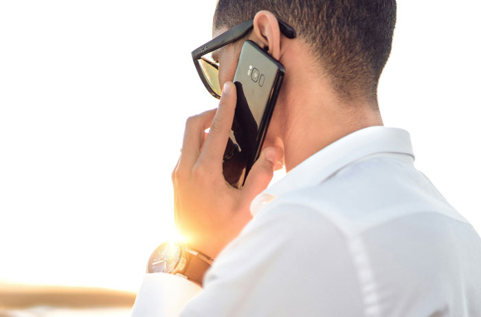 Man in white shirt and glasses holding smartphone to ear, representing disturbing voicemails people have received.