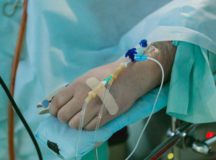 Patient's hand with IV lines in hospital bed, symbolizing chilling truths hidden in plain sight after death exposure.