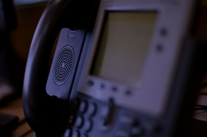 Close-up of a modern office phone handset and screen, related to unhinged and disturbing voicemails received.