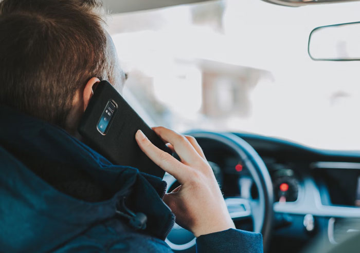 Person in a car holding phone to ear, illustrating unhinged and disturbing voicemails people have received.