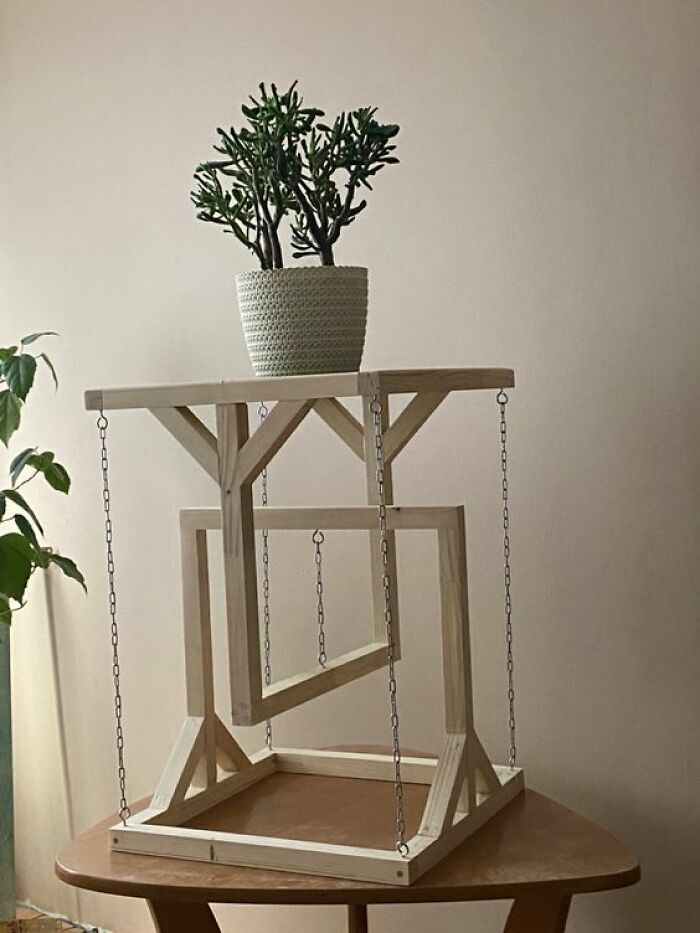Woodworker project showcasing a unique wooden planter stand with suspended geometric frames and metal chains.