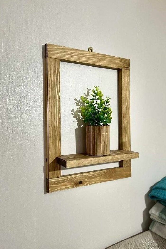 Woodworkers handmade wooden wall frame shelf holding a small potted plant, showcasing a cool woodworking project.