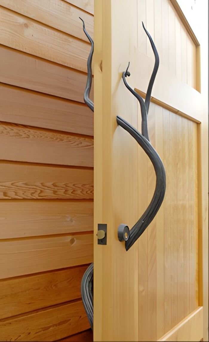 Woodworker project featuring a wooden door with artistic black twisted metal handle and natural wood panel wall background.